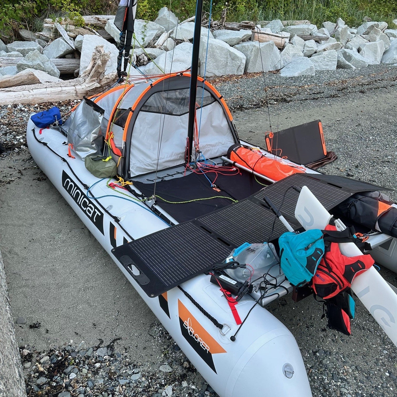 Inflatable catamaran 520 Explorer with solar panels and Remigo on a rocky shoreline - customer photo