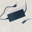 Black power adapter with multiple cables on a light gray background
