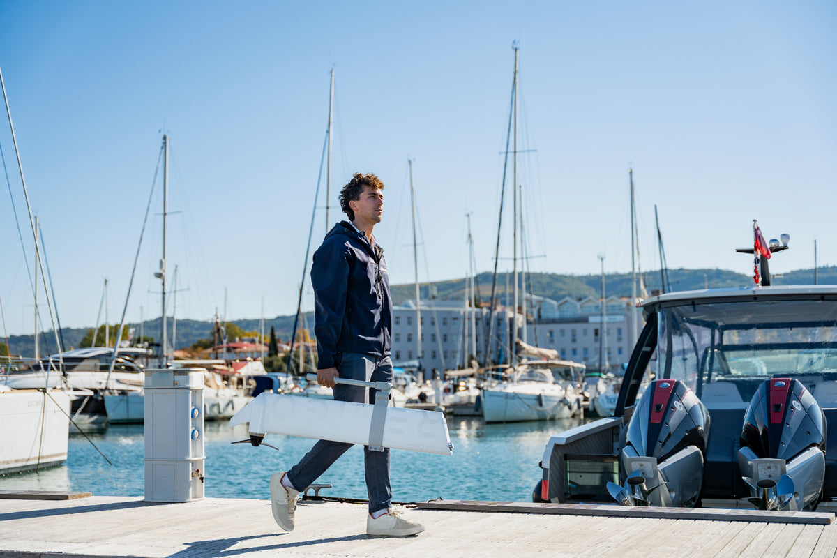 Person holding Remigo outboard in a marina with boats and clear sky