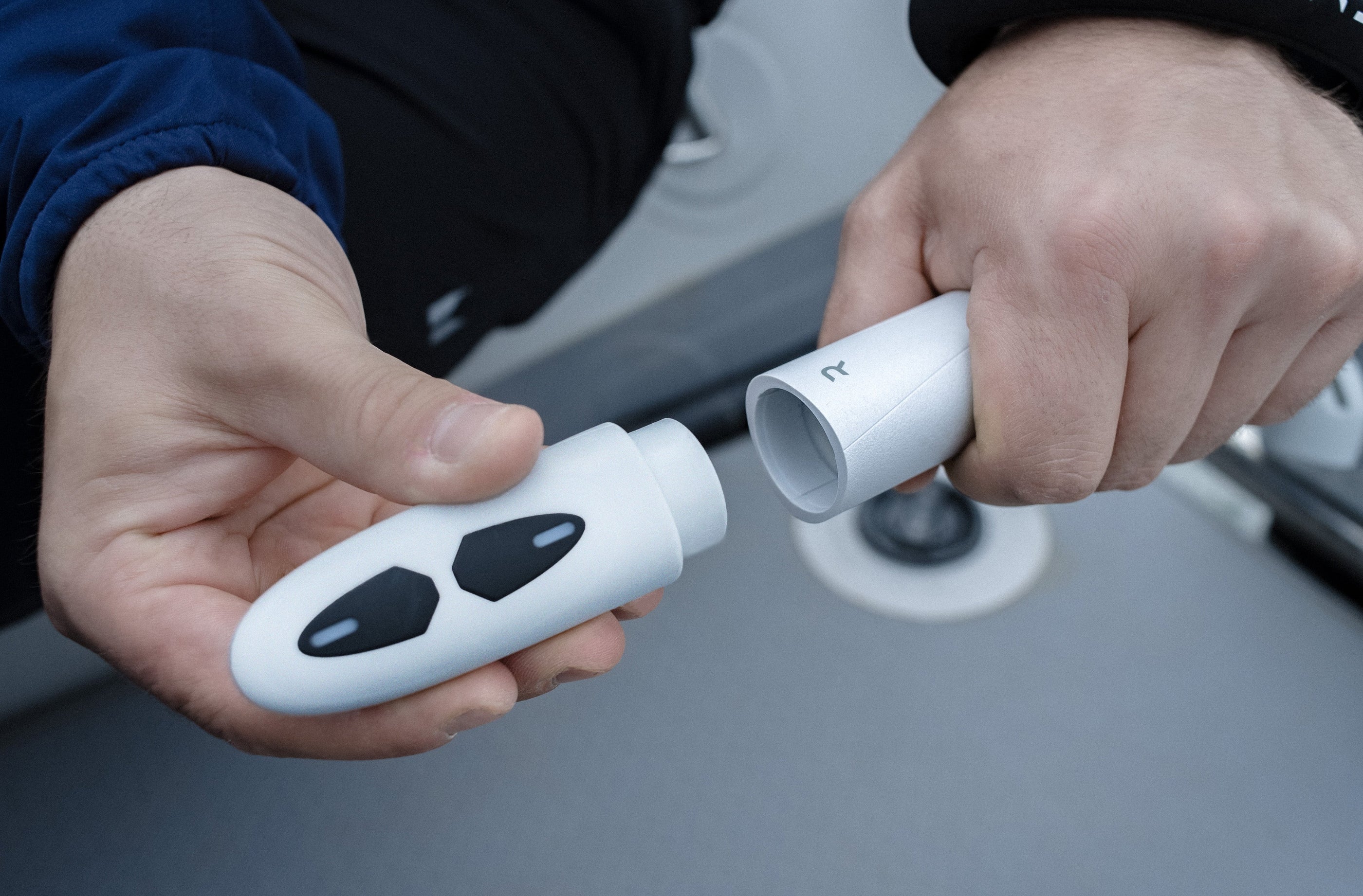 Two hands holding white electronic devices with black buttons on a blurred background