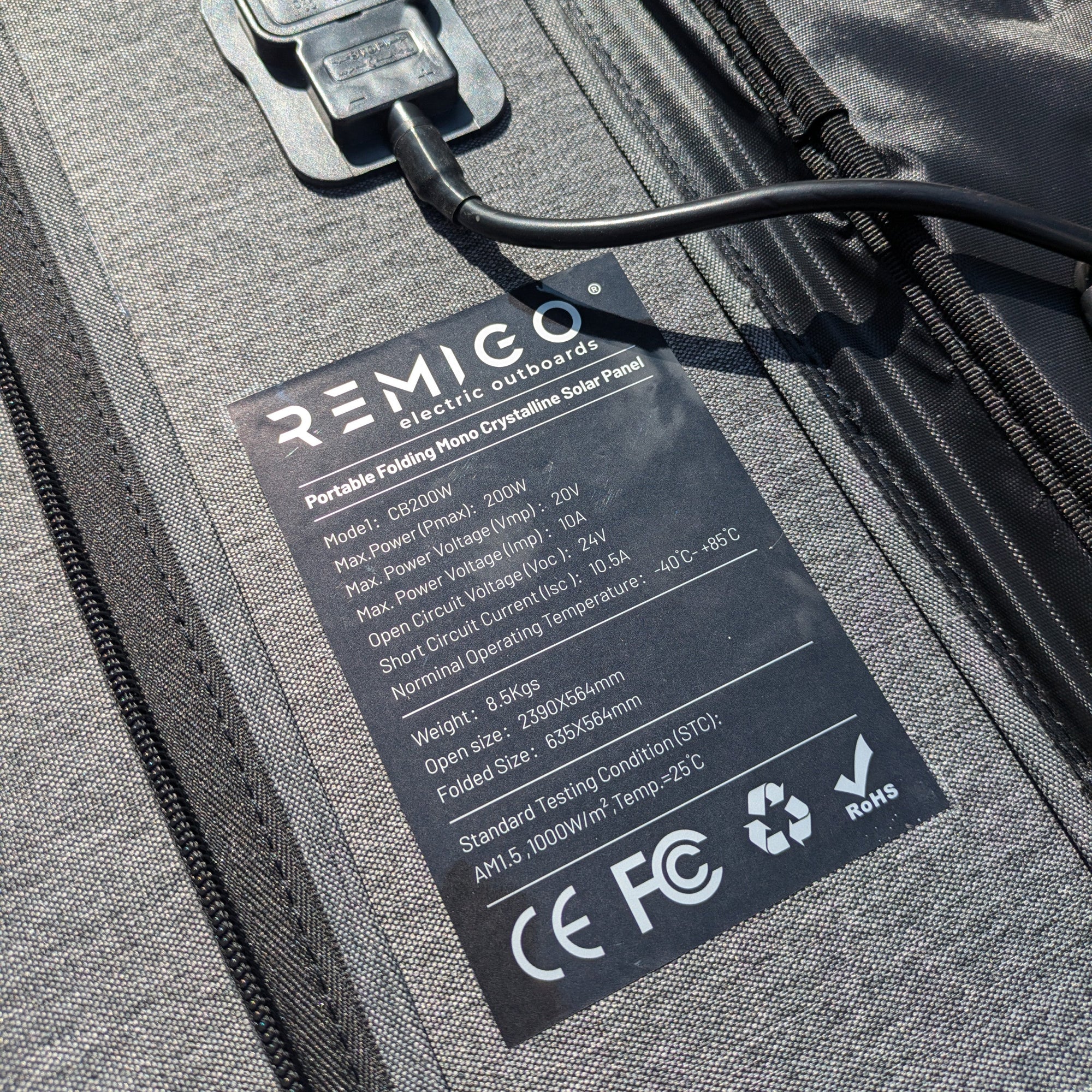 REMIGO electric outboard solar panel with charging cable and label on a gray surface